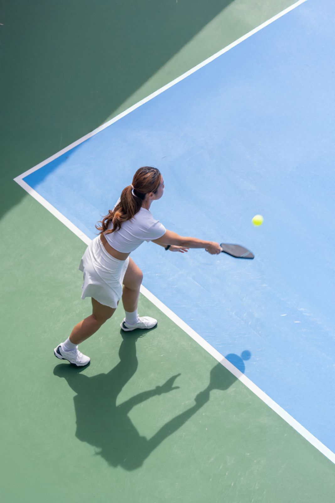 Image of an Asian female pickleball player serving pickleball game. Outdoor