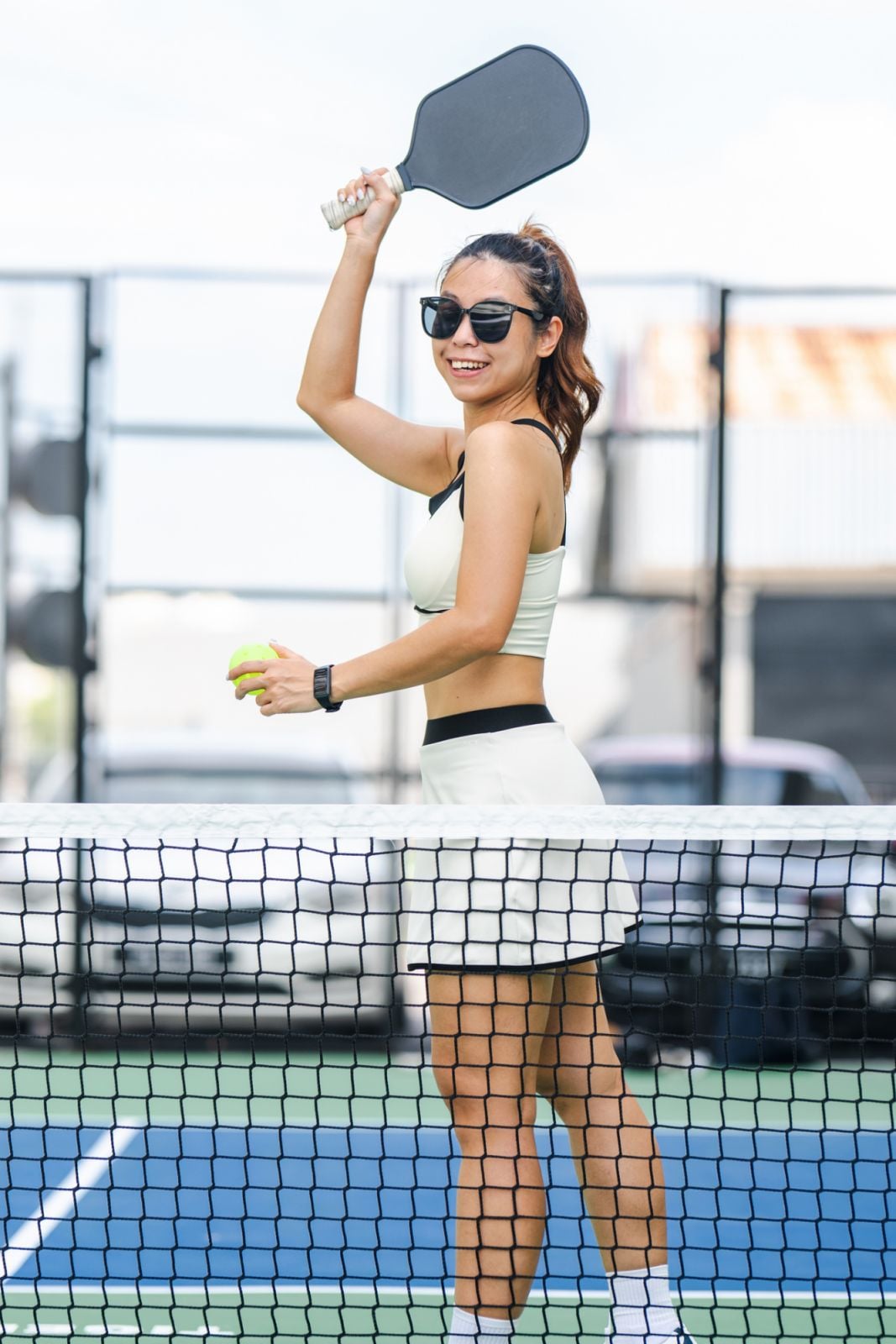 Shot of a beautiful Asian female pickleball player serving pickleball game. Outdoor