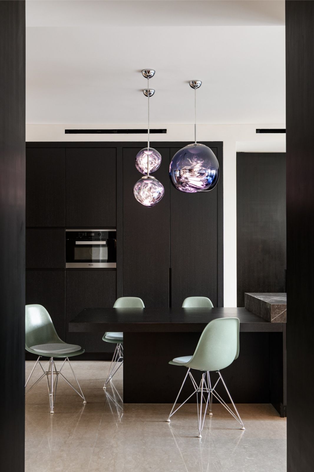 Modern dining area with mint Eames-style chairs and striking purple hand-blown glass pendants
