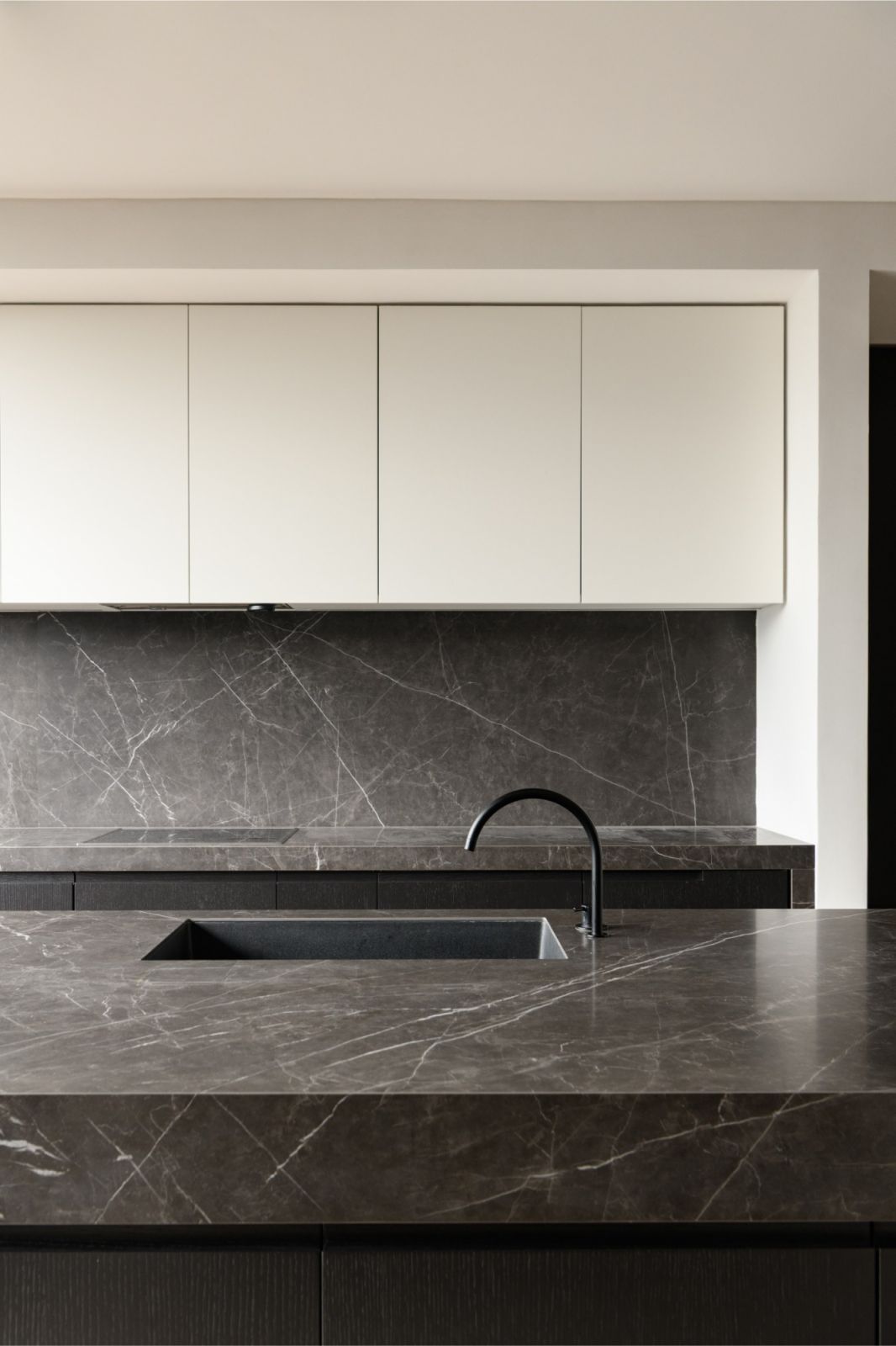 Contemporary kitchen featuring grey marble countertops against minimalist white cabinetry in this Malaysian luxury penthouse renovation