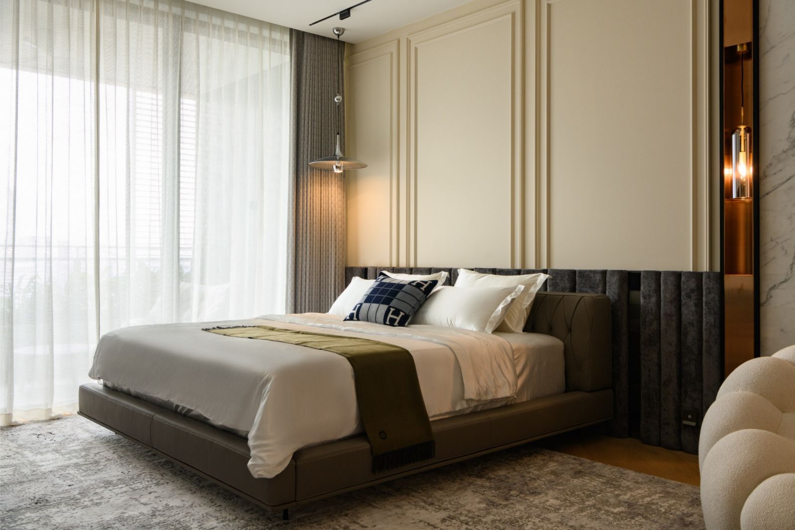 Sophisticated bedroom with channelled headboard and custom wall treatments