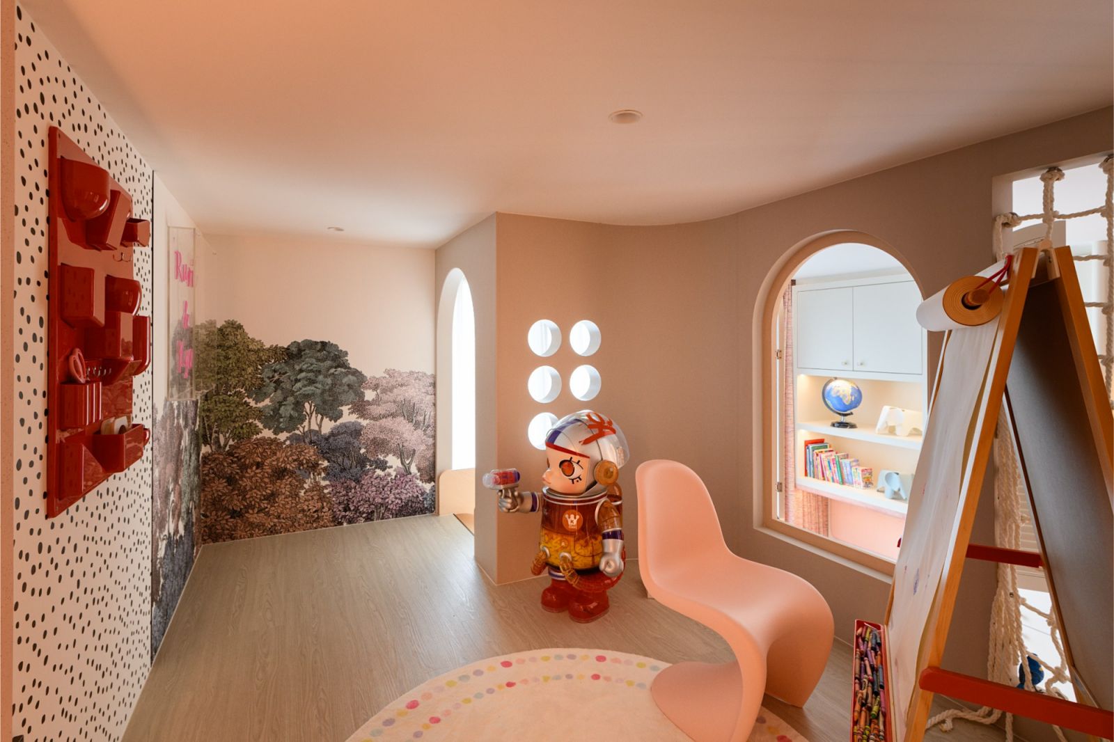 Playful children’s space with a forest mural and a pink Panton chair