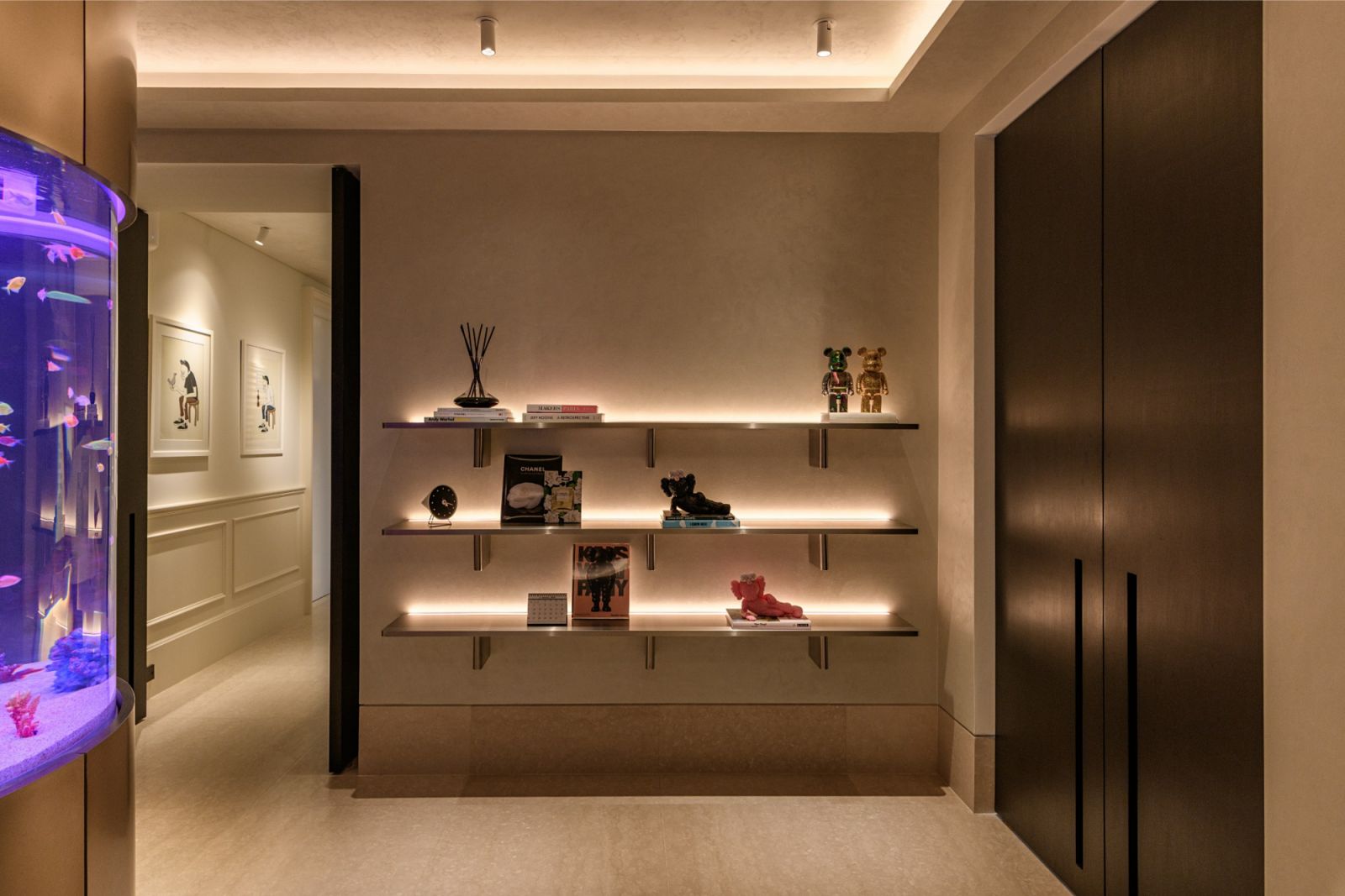 Illuminated art shelves and collectible figurines display with a custom cylindrical aquarium in the gallery corridor of this Kuala Lumpur residence