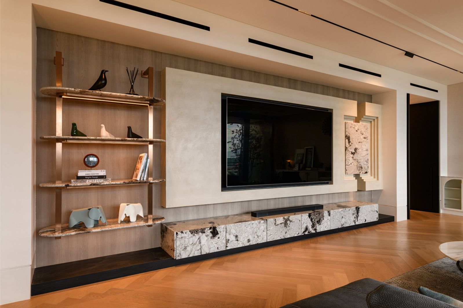 Media wall featuring custom shelving, marble accents and oak flooring in herringbone pattern in this penthouse by Solid Design Studio