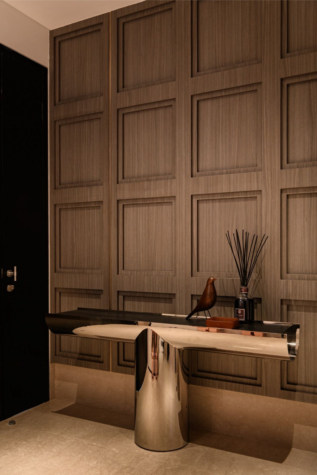 Custom wood panelling and metallic console in the foyer featuring copper-accented waterjet marble flooring in the Japanese family’s luxury residence