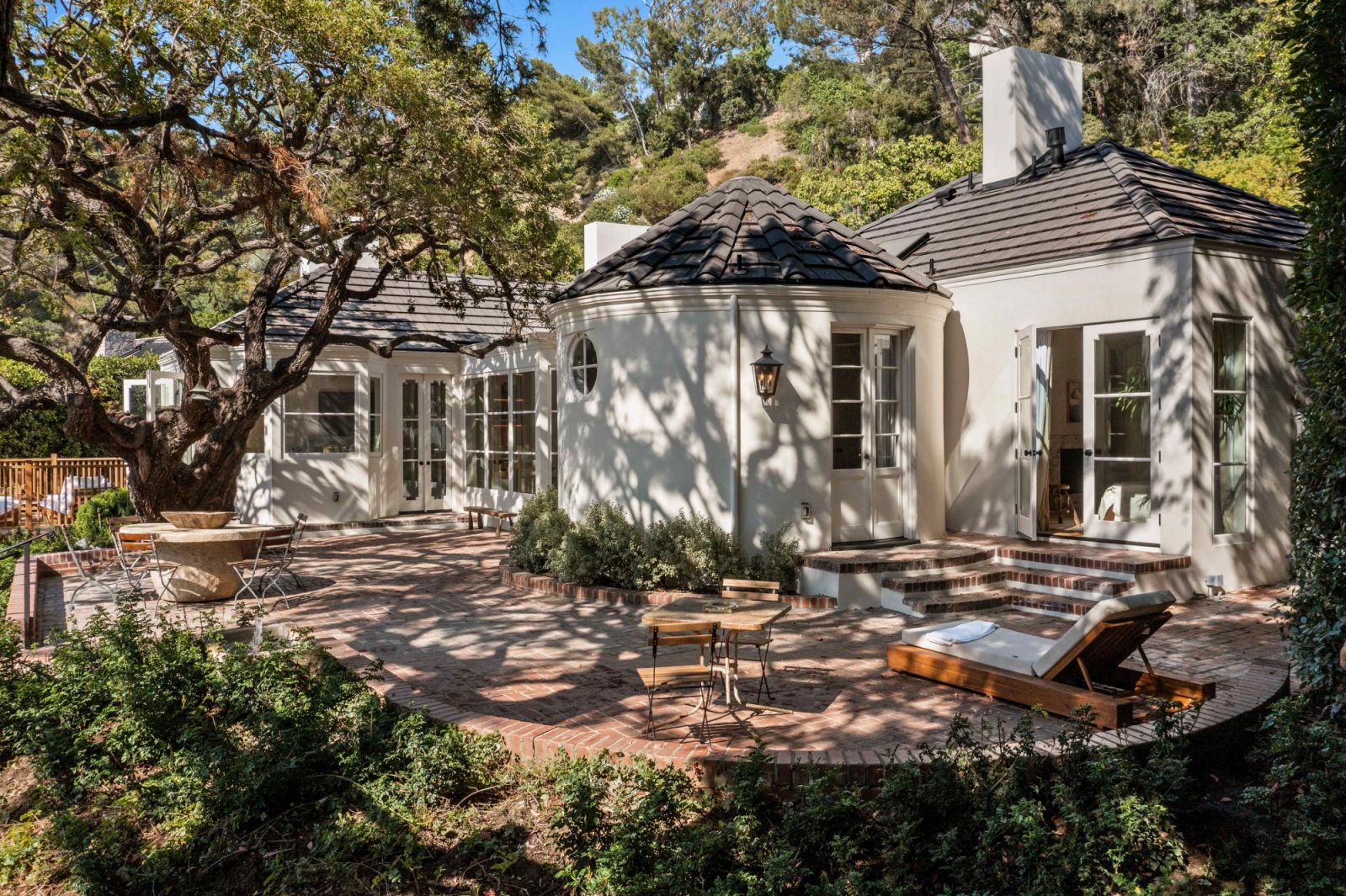 The double-lot property features tall chimneys and roof rafters with white stucco details