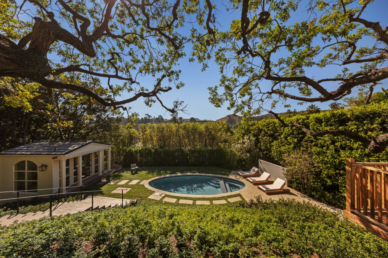 The expansive backyard with an oval French grey-bottom swimming pool