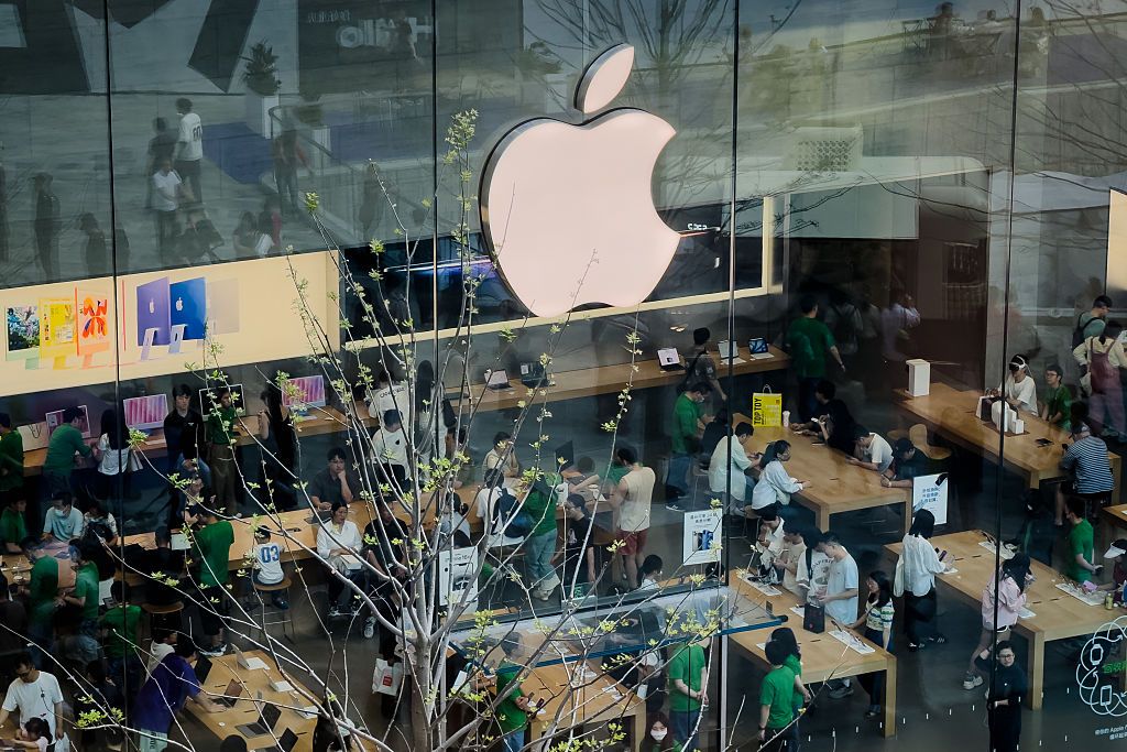CHONGQING, CHINA - APRIL 19: Customers interact with Apple products inside a packed Apple Store, seen through its glass facade with a prominent white Apple logo, on April 19, 2025 in Chongqing, China. The store showcases the latest iMac models and Apple Vision Pro headset as the company continues to attract strong consumer interest across major Chinese cities. (Photo by Cheng Xin/Getty Images)