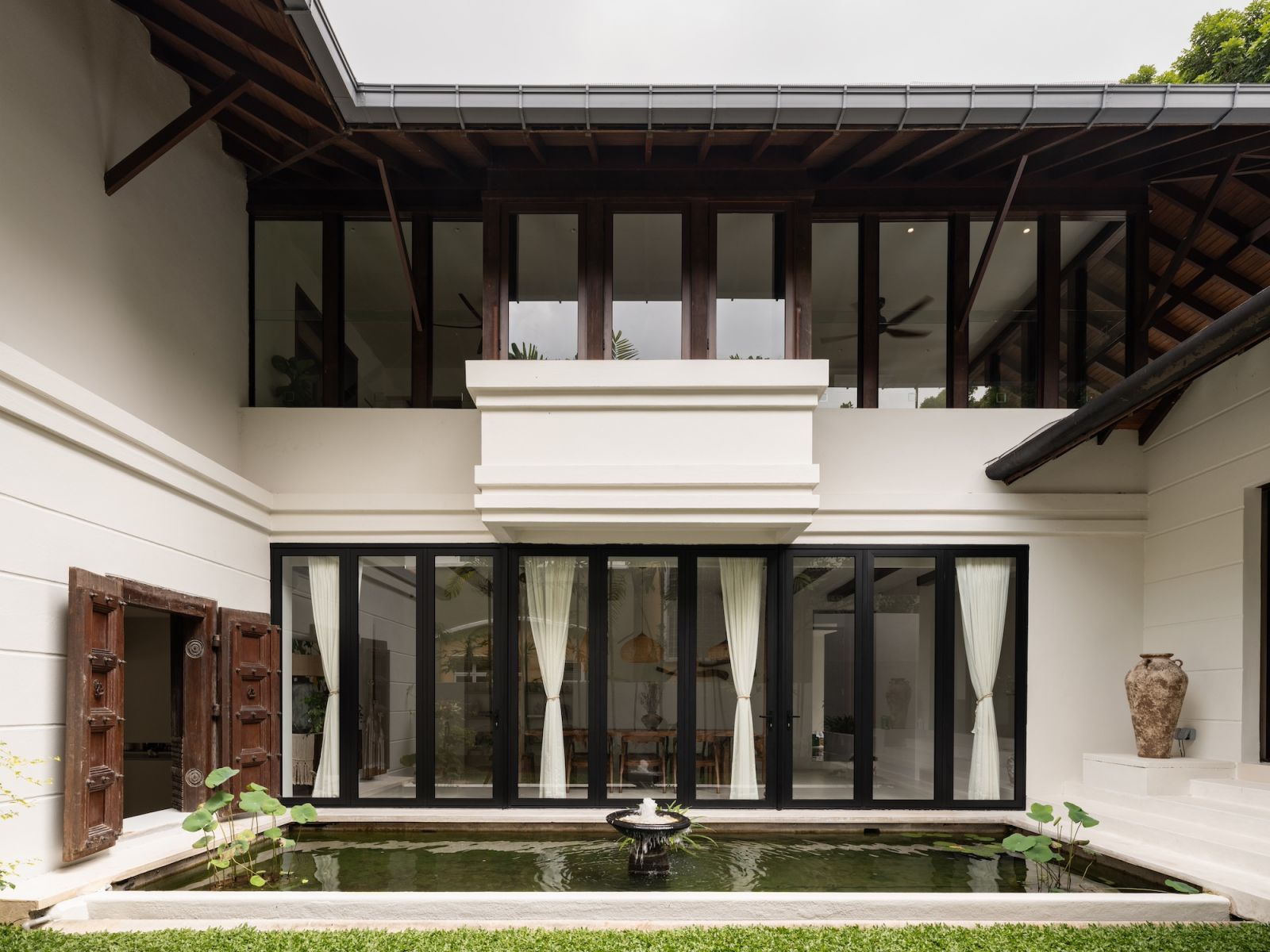 The reflecting pool beside the open-concept dining area visually extends the living space into the lush surrounding landscape