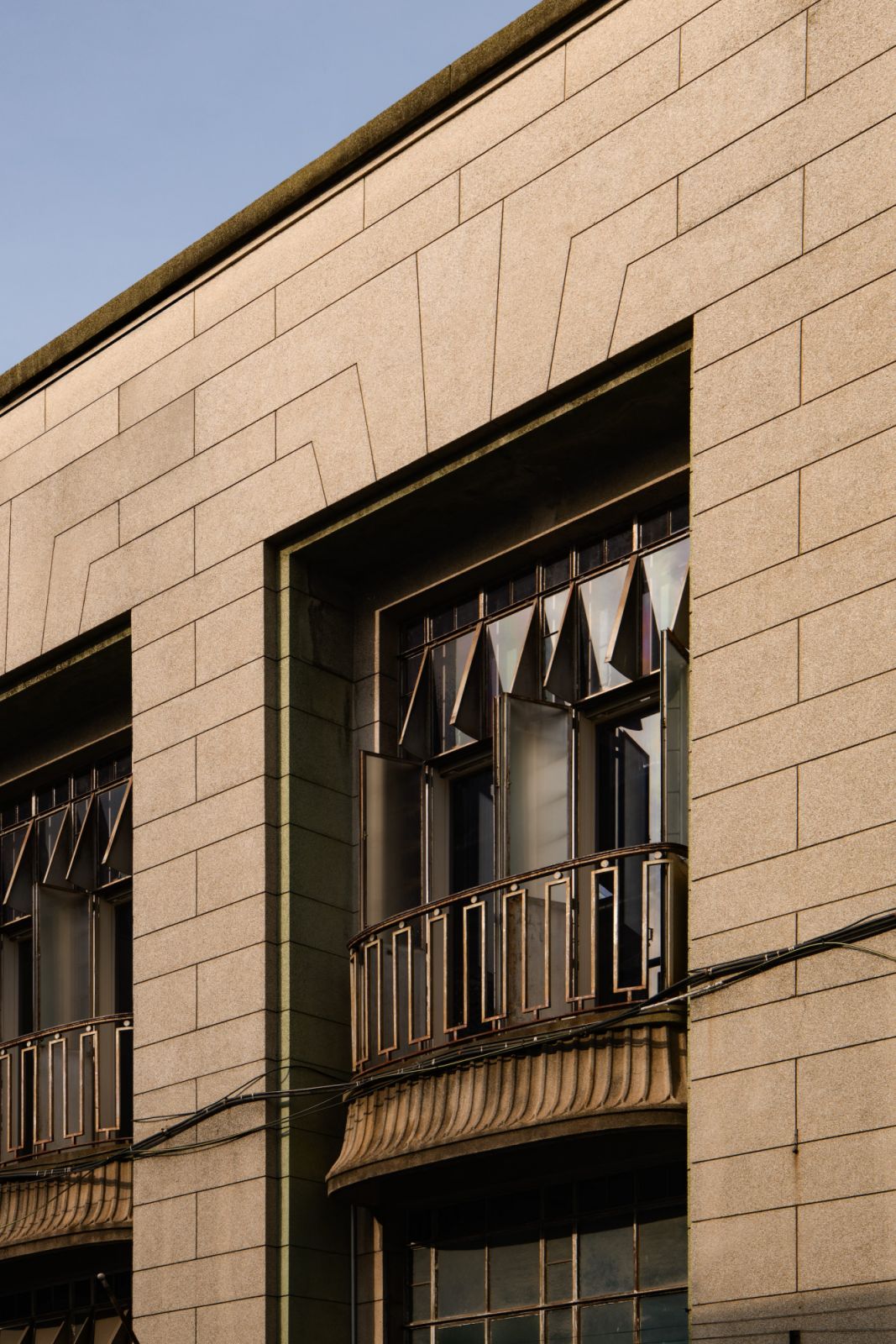 Original window details and structural elements are complemented by a restrained material palette of whitewashed timber, patinated wood, and stone