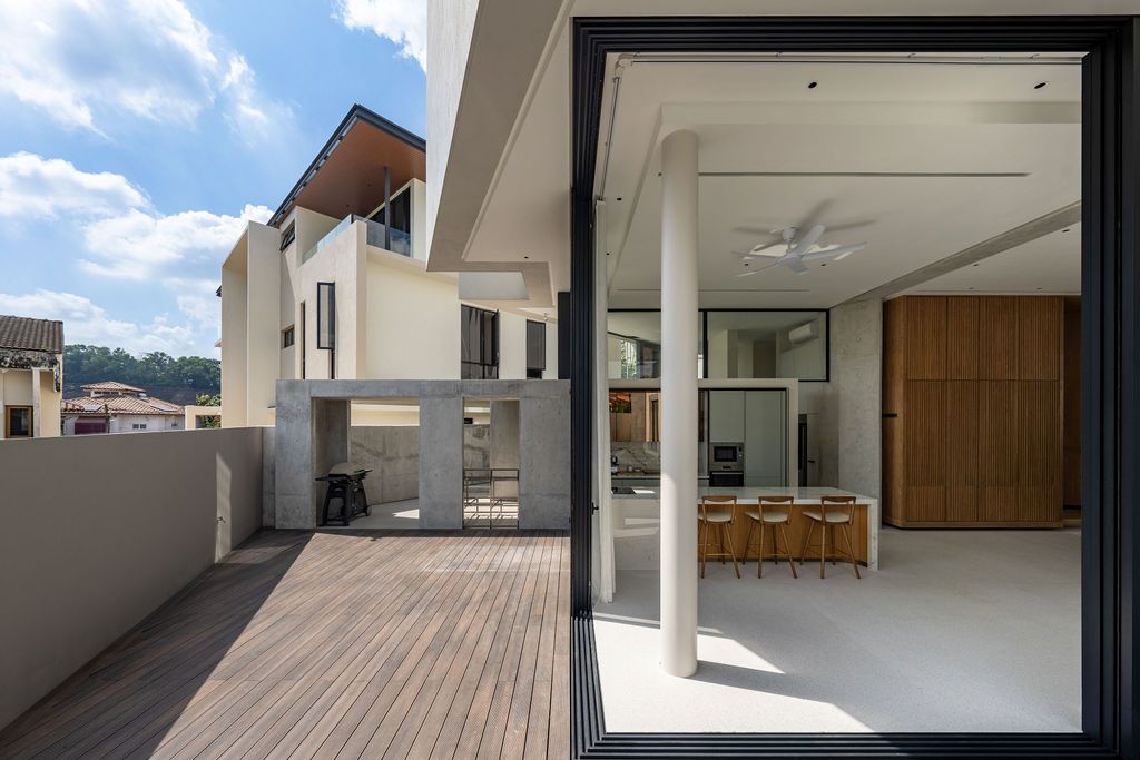 The timber-decked terrace extends from the kitchen with concrete blade walls supporting the floating upper volume