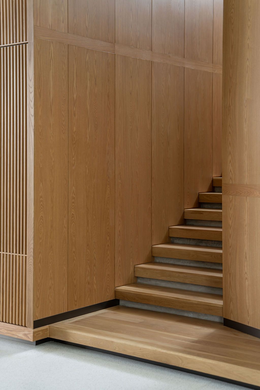 The oak-lined staircase enclosure demonstrates Wong’s material restraint with sculptural wood elements