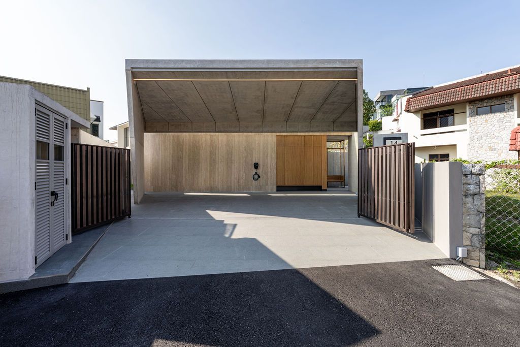 The minimalist entrance showcases Wong's bold architectural gesture where fair-faced concrete creates a protected carport beneath the overhanging upper volume