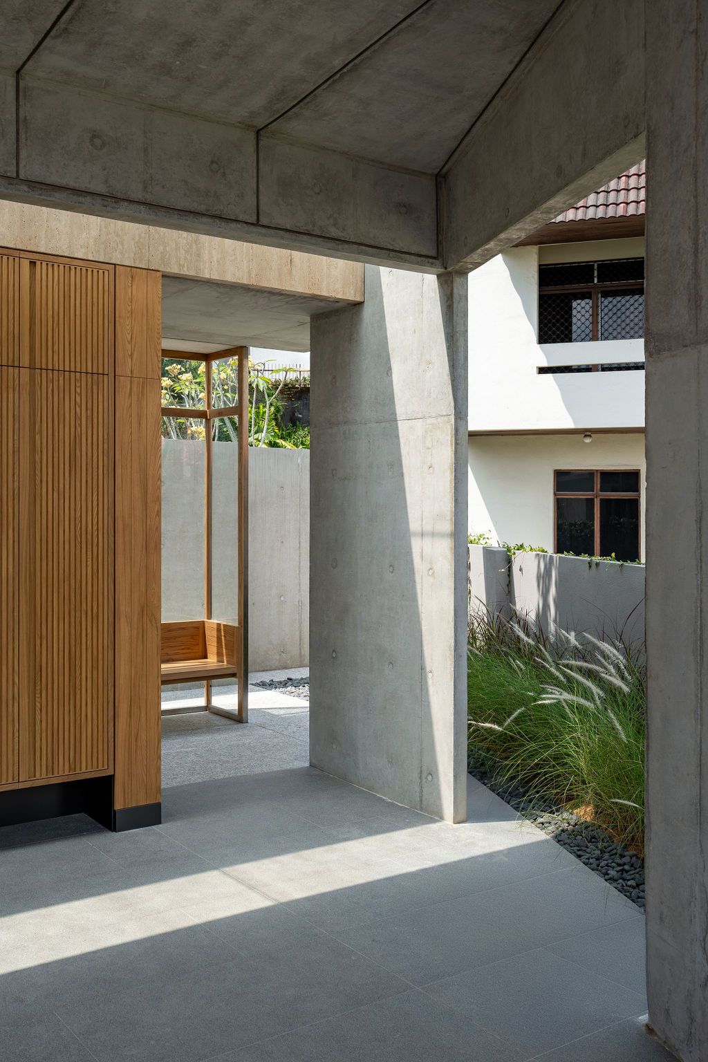 The threshold between interior and exterior spaces showcases the structural blade walls that support the floating upper volume