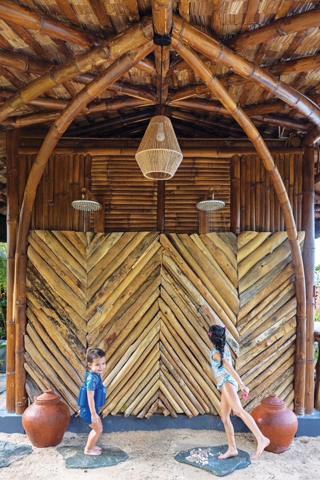 Orion and Savanna playing in the driftwood outdoor shower at Aman Sinaya on Mati Island, Mindanao