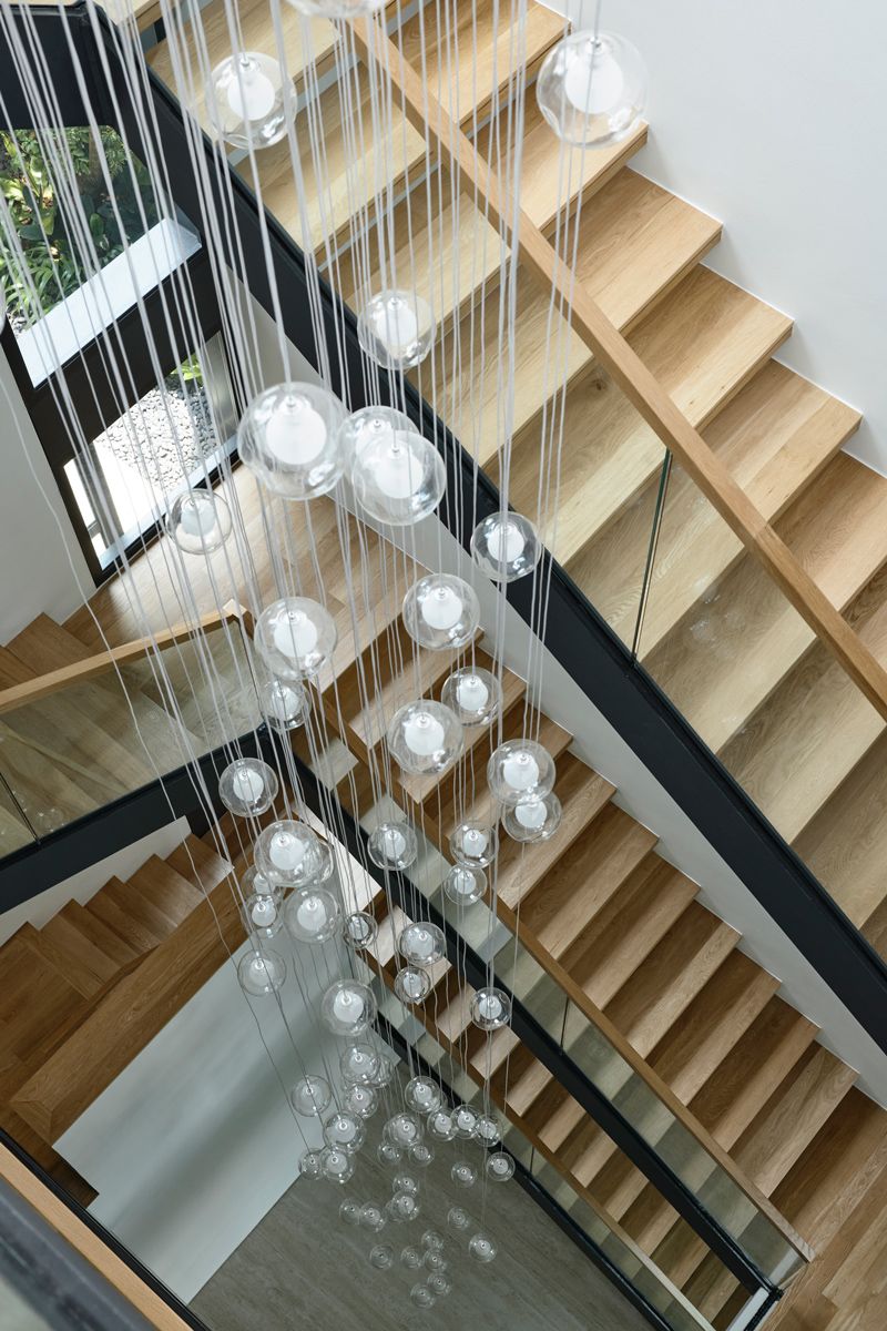Pendant lights cascades through the central staircase, amplifying the verticality and openness of the bungalow's core