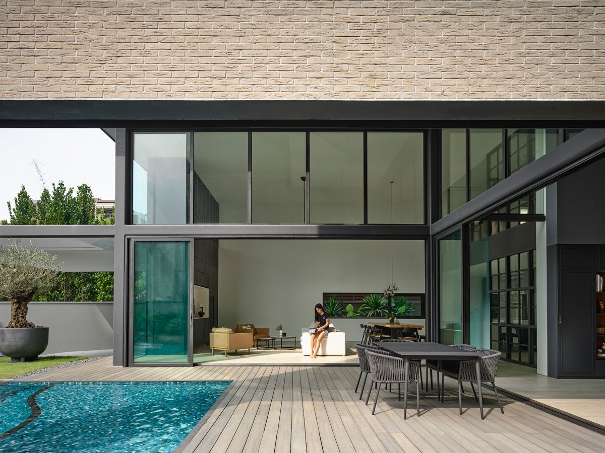 The bungalow's double-height living room opens fully to the decked terrace, garden, and organically shaped pool