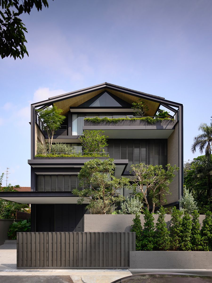 The gabled roof stretches downward in steel-framed ribs, shading staggered terraces and pockets of greenery