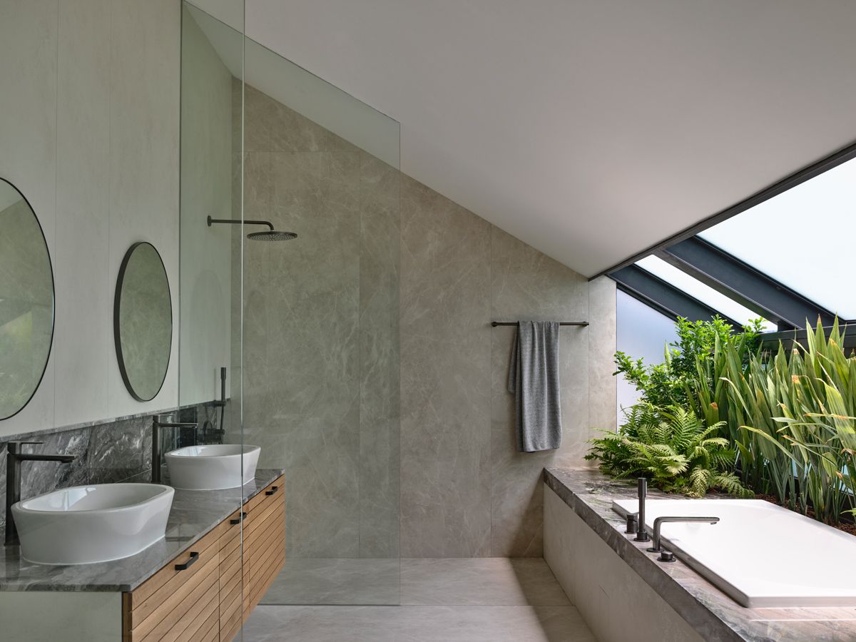 In the bungalow's attic master bathroom, a skylight beside the tub invites sunlight and greenery into the space