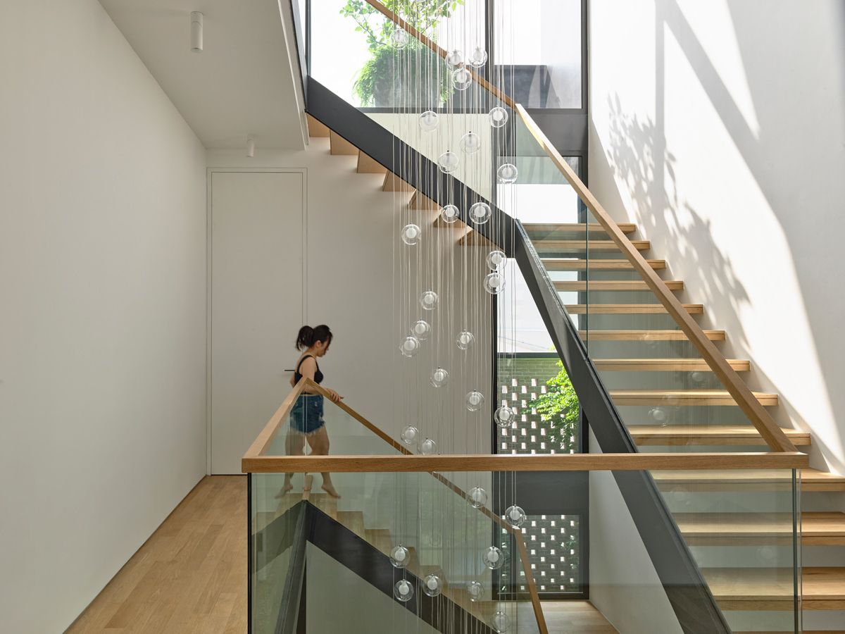 Centrally positioned, the open-riser staircase enhances vertical connection across levels and draws in daylight from a skylight above