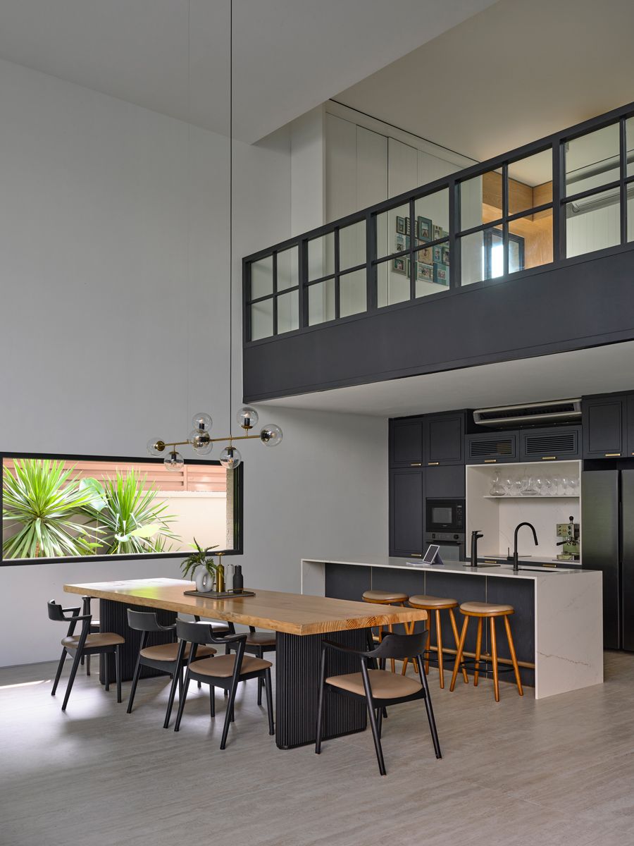The double-volume dining area connects to a sleek open kitchen, with the family room overlooking the space from above
