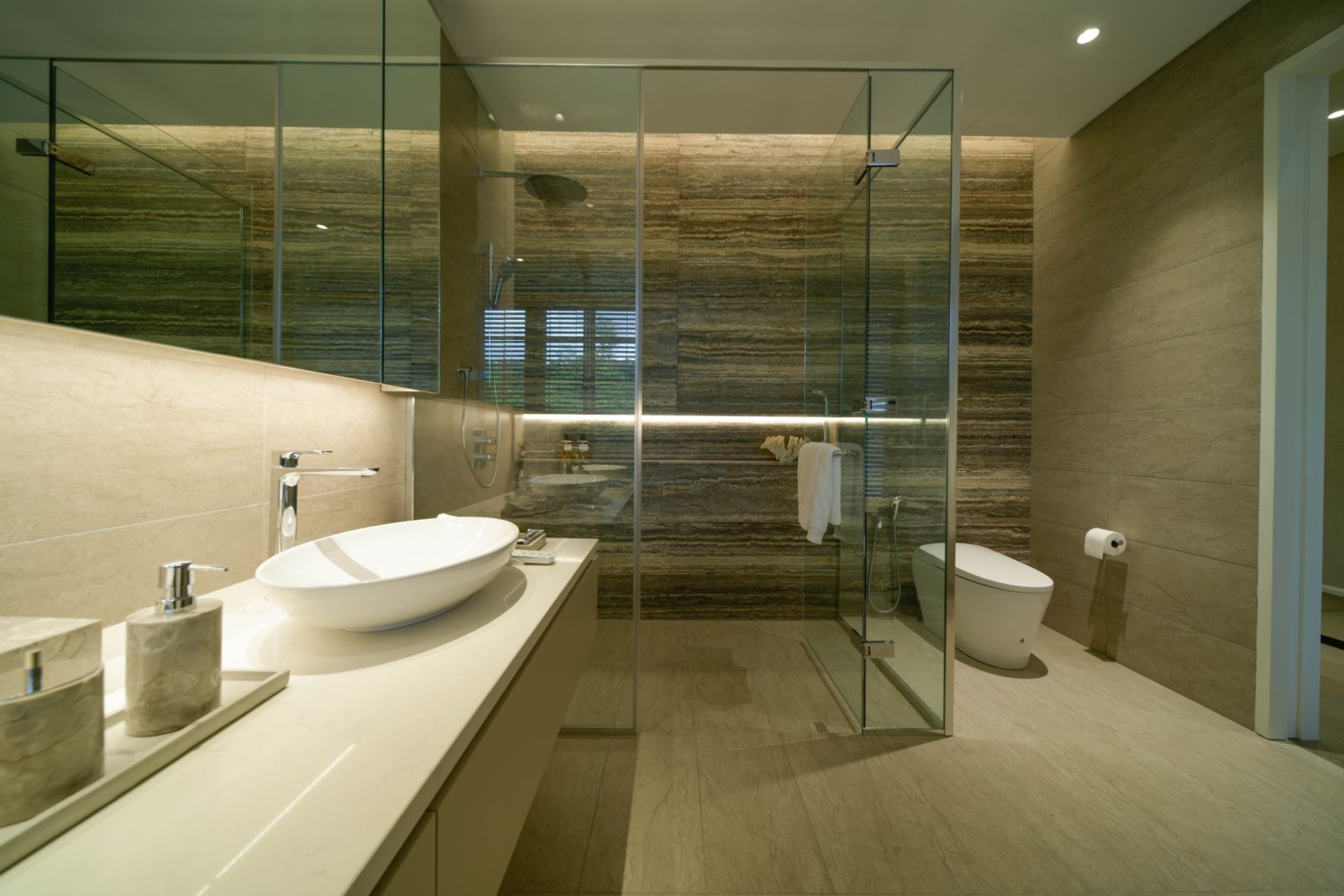A bathroom defined by clean lines and a restrained palette, featuring a glass-enclosed shower, vessel sink, and wall-mounted fixtures with natural stone surfaces