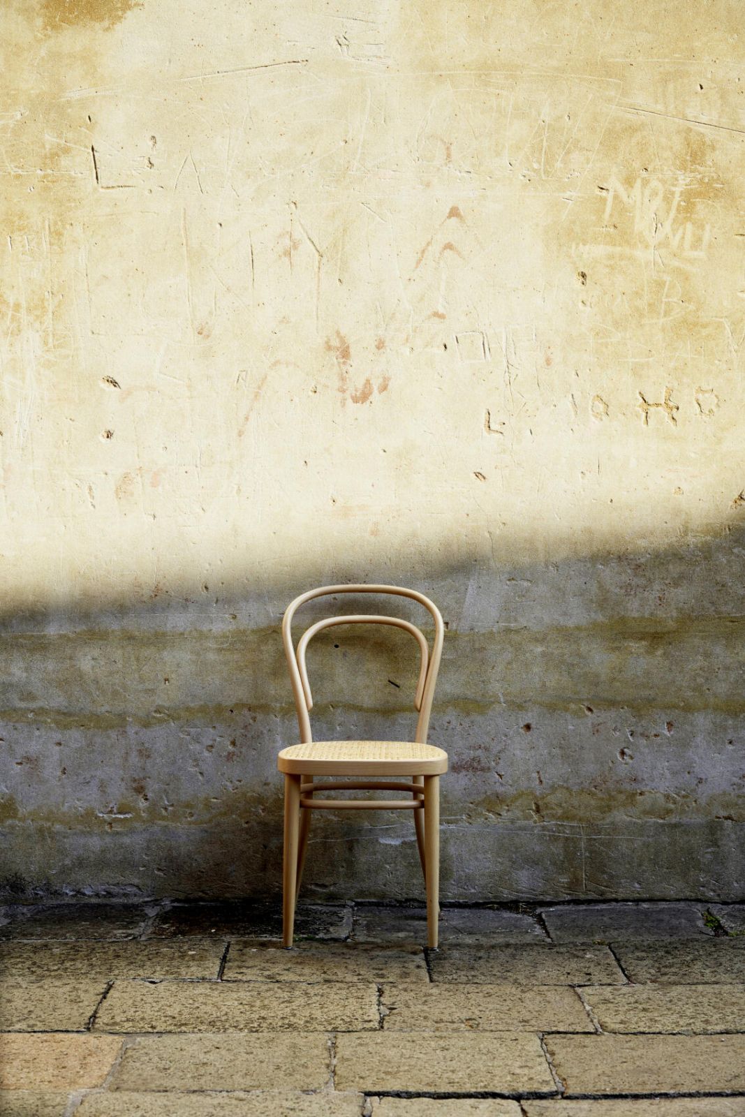 The timeless silhouette of the Thonet Chair No. 14, pictured against a weathered stone wall, highlights its minimalist elegance and universal appeal (Photo: Thonet)