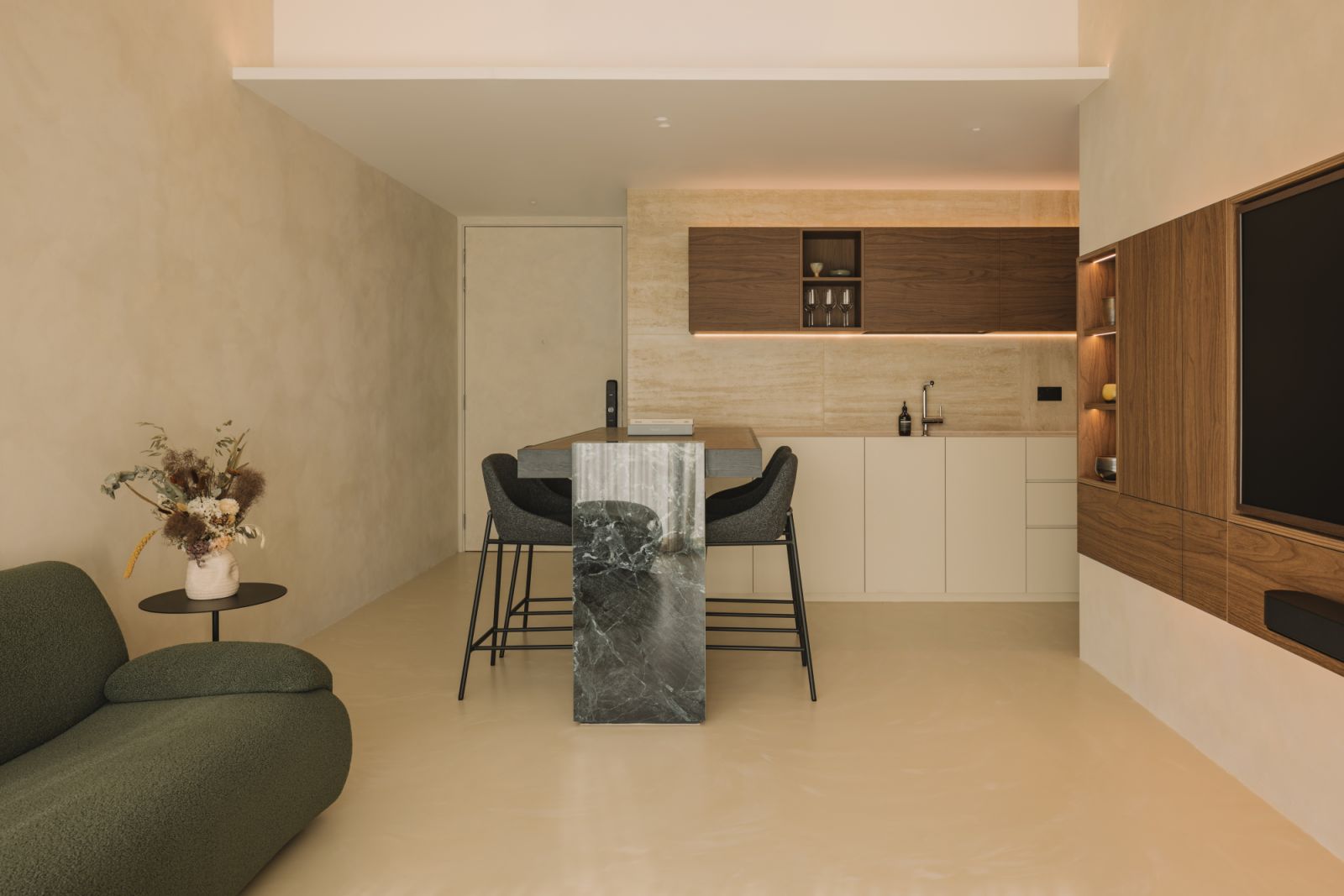 From the marble counter to the oak cabinetry, every detail in the open kitchen is considered for both form and function. A subtle glow from concealed lighting breathes warmth into the kitchen’s natural textures, highlighting the interplay of wood, stone, and plaster