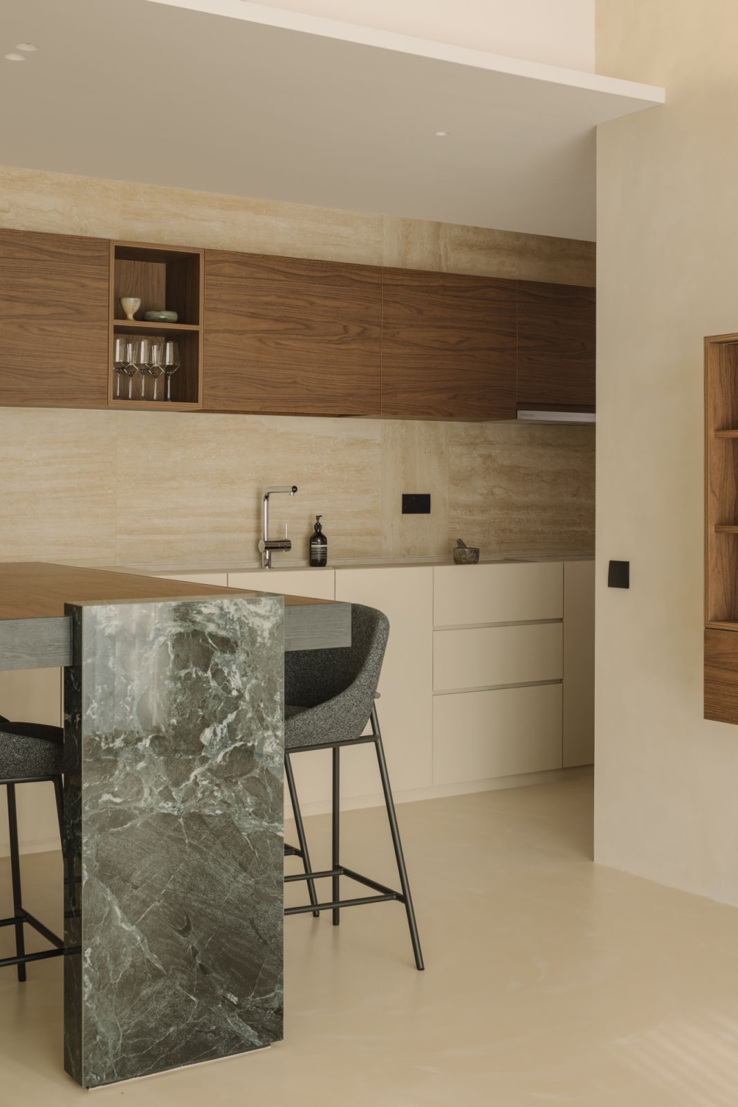 With its expressive veining and monolithic presence, the dark marble kitchen island adds visual weight and grounding to the otherwise light-toned space