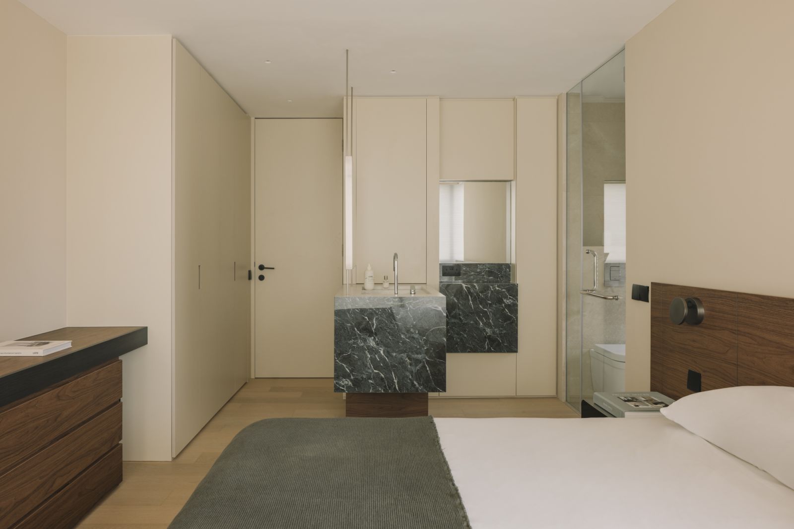 Framed by full-height cabinetry, the ensuite vanity in richly veined green marble anchors the bedroom with sculptural boldness and tailored utility