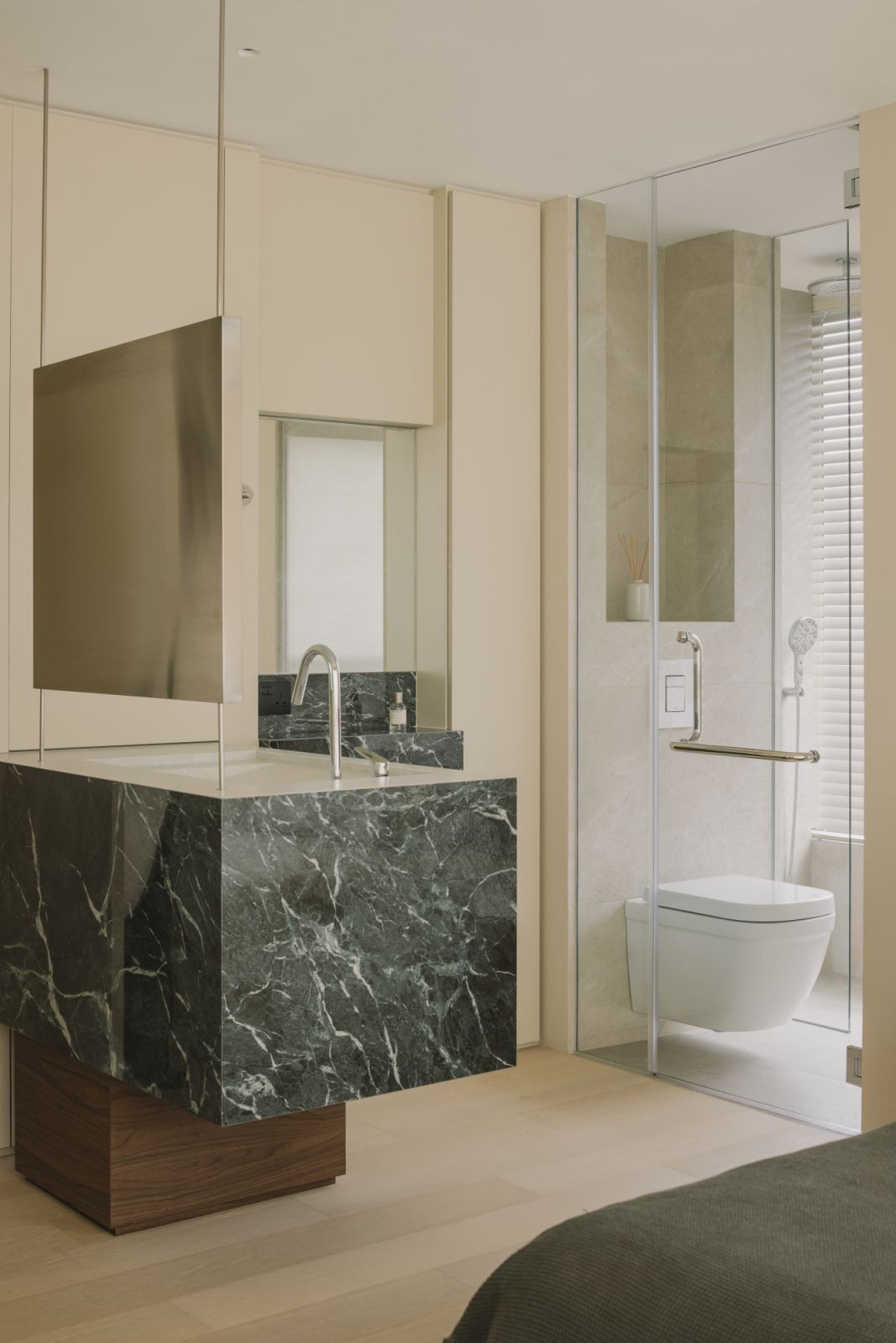 Sleek fixtures, clear glass partitions, and a palette of stone tones lend the ensuite bath a modern spa-like serenity