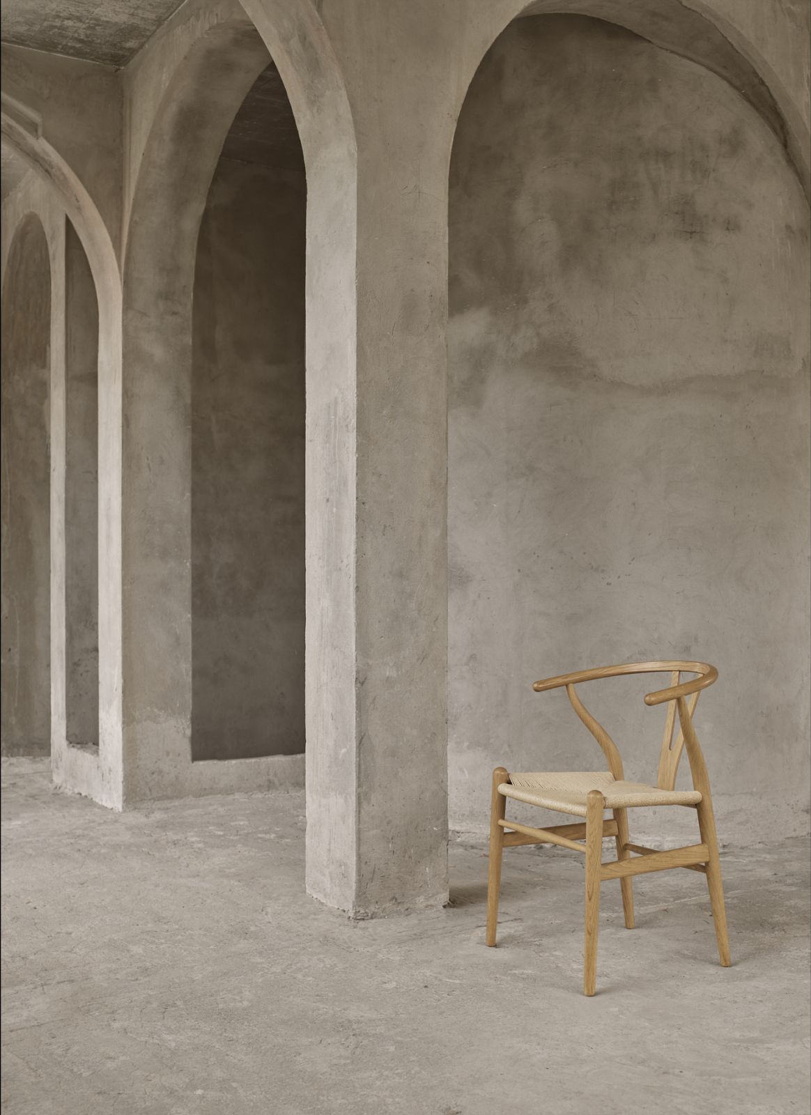 The architectural beauty of a single Wishbone chair is highlighted against dramatic concrete arches (Photo: Carl Hansen & Søn)