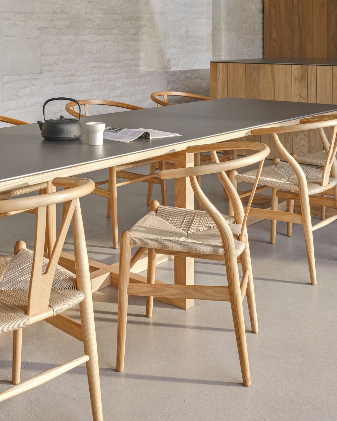 The handwoven paper cord seats and sculptural oak frames of the Wishbone chairs create an elegant contrast against textured stone walls (Photo: Carl Hansen & Søn)