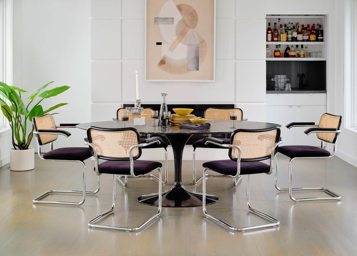 A dining room featuring six Cesca chairs around a sleek black Tulip table demonstrates how this iconic 1920s design adapts beautifully to modern interiors (Photo: Knoll)