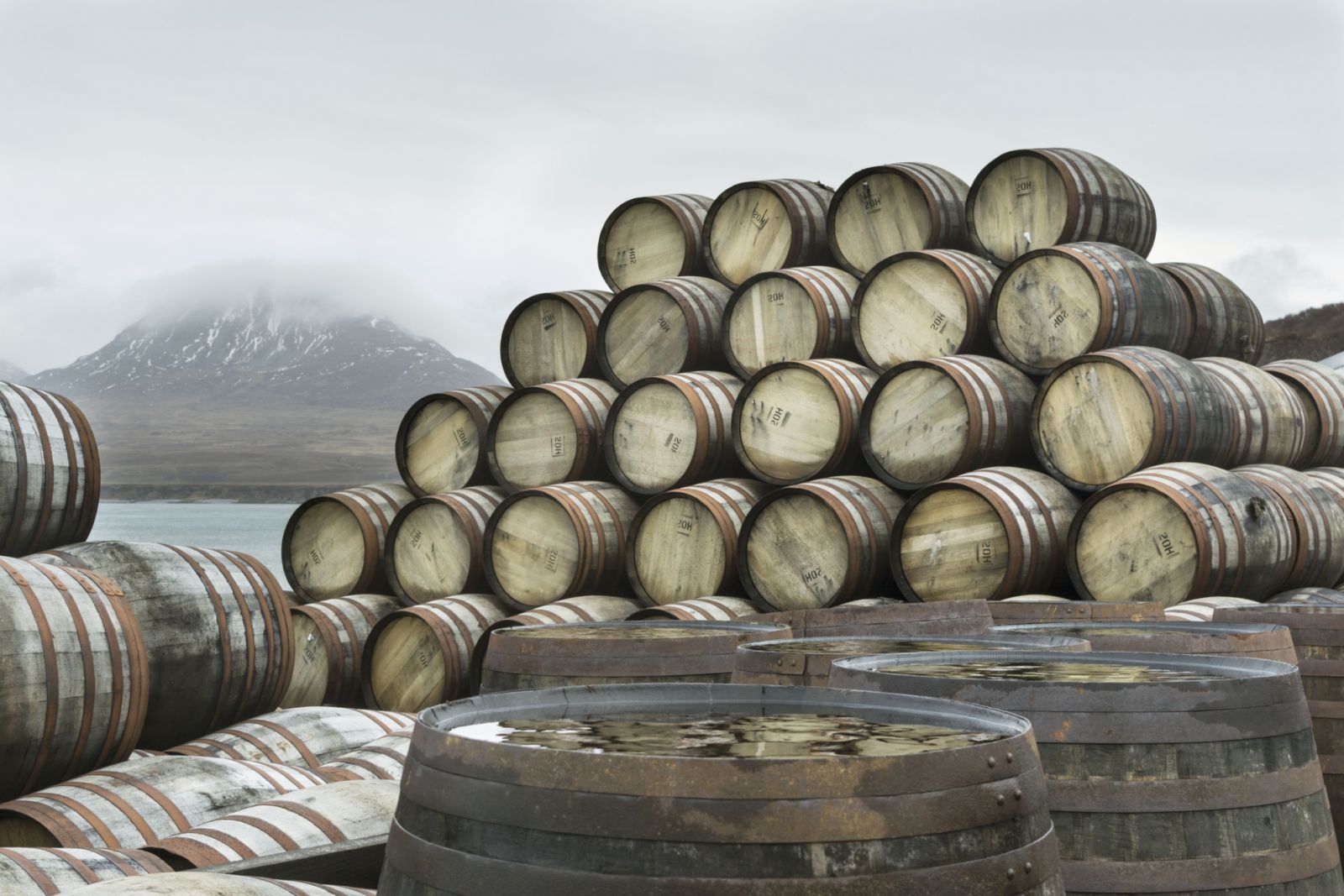 Whisky casks have been stacked up outside Bunnahabhain distillery on the north of the Isle of Islay waiting to be filled with Whisky and transported for storage.