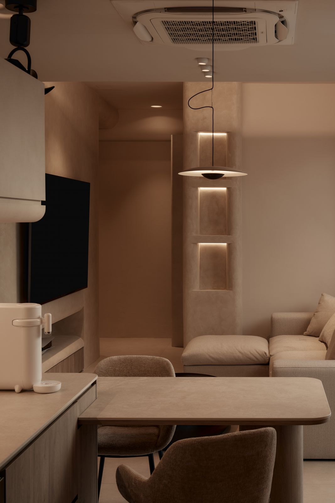 A custom dining table floats beside the open-plan living space, bathed in warm ambient lighting that complements the home’s tonal restraint