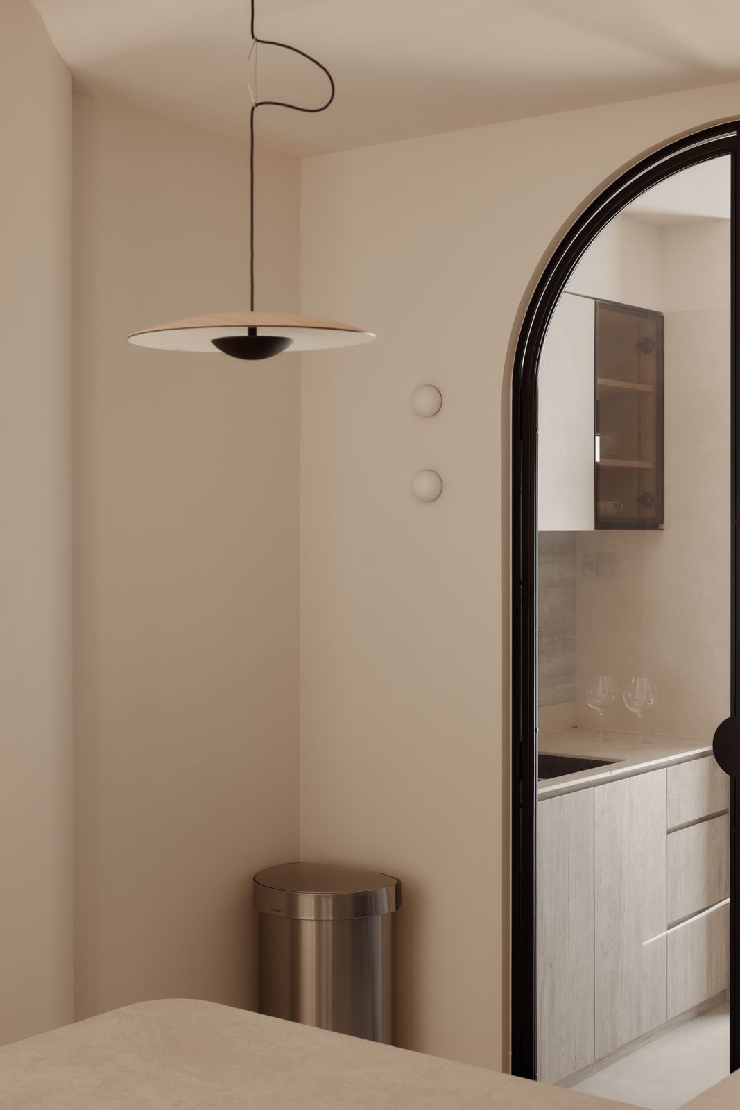 A sculptural pendant adds a whimsical touch to the otherwise grounded palette, highlighting the meticulous layering of finishes