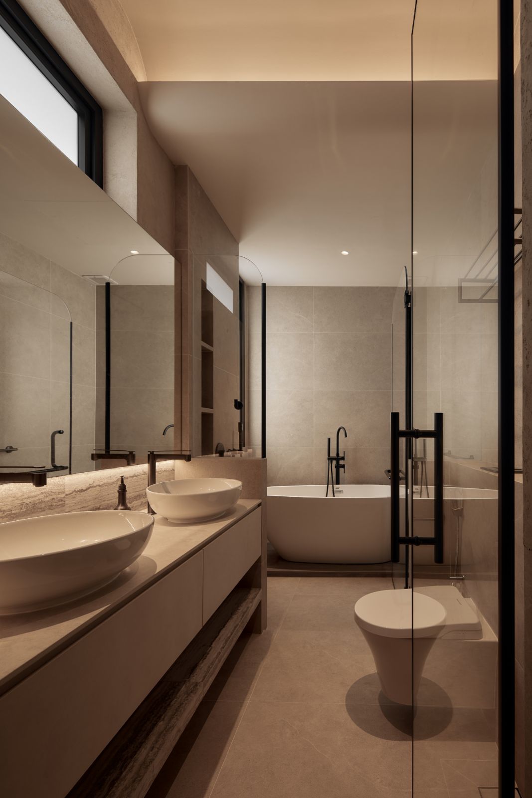 The bathroom features a floating vanity and fluted lighting that elevates the warm stone textures and sculptural fittings