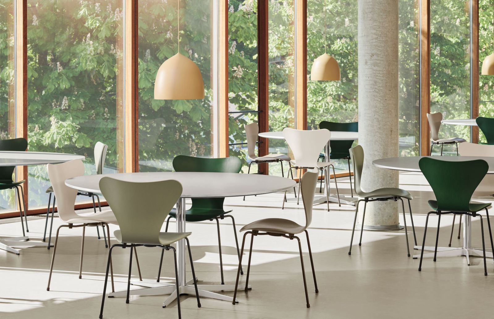 A modern café setting showcases the versatility of Arne Jacobsen’s Series 7 chairs in multiple colourways—sage green, cream, and forest green (Photo: Fritz Hansen)