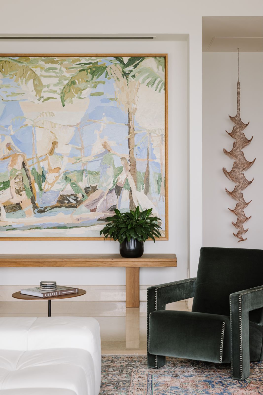 A green velvet armchair invites repose beneath a soft, painterly artwork—one of many design gestures that speak to the home’s layered global story