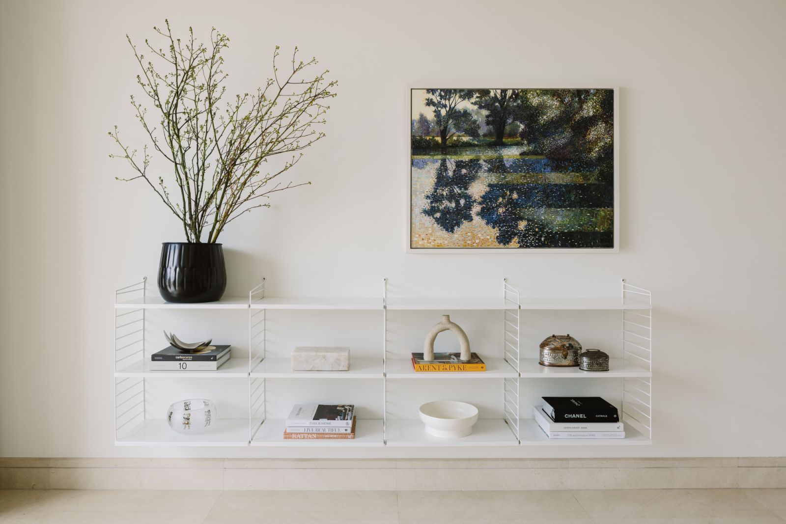 Thoughtfully layered with curated objects, this open shelving unit captures the essence of mindful collecting—where every piece, from ceramics to coffee table tomes, contributes to a quiet visual rhythm