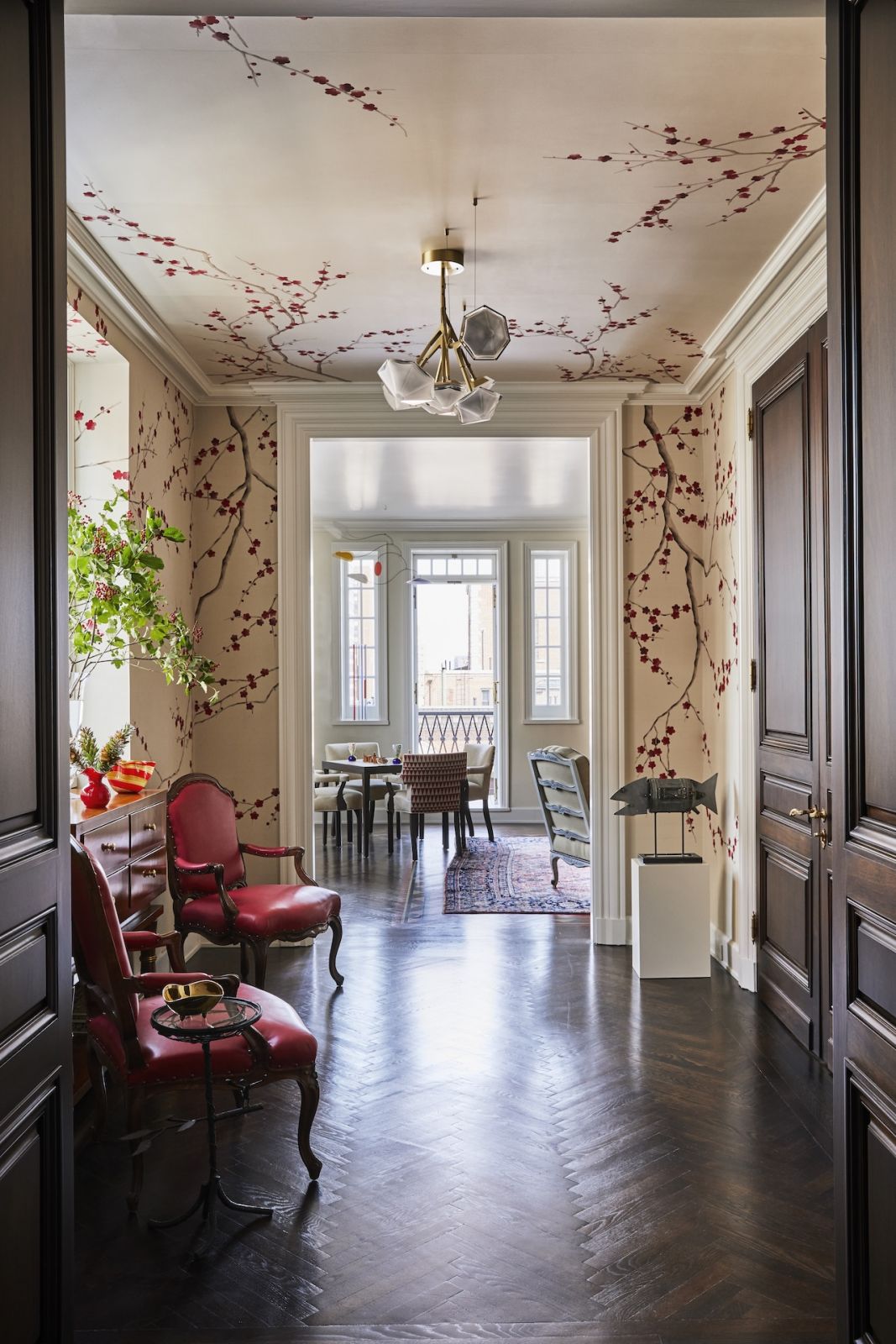 The entryway to a Japanese-inspired home on Park Avenue, New York designed by Phillip Thomas, with hand-painted cherry blossoms designed in collaboration with De Gournay and a chandelier from the Myriad Series by Gabriel Scott