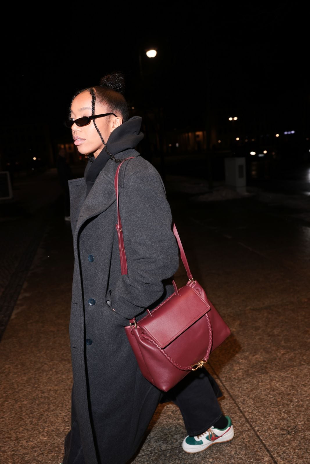 BERLIN, GERMANY - FEBRUARY 14: Naomi Ackie is seen at Kempinski Hotel Bristol wearing the Bottega Veneta leather Andiamo in bordeaux / burgundy red, grey oversized wool coat, black glasses and white sneaker on February 14, 2025 in Berlin, Germany. (Photo by Jeremy Moeller/Getty Images)