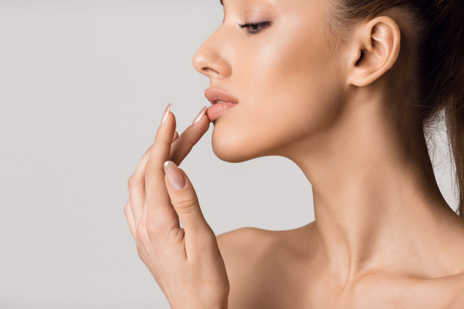 Lip augmentation. Beautiful girl touching her lips over gray background, copy space