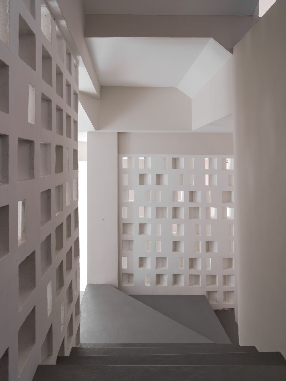 Light and shadow dance through the geometric breeze blocks, creating ever-changing patterns