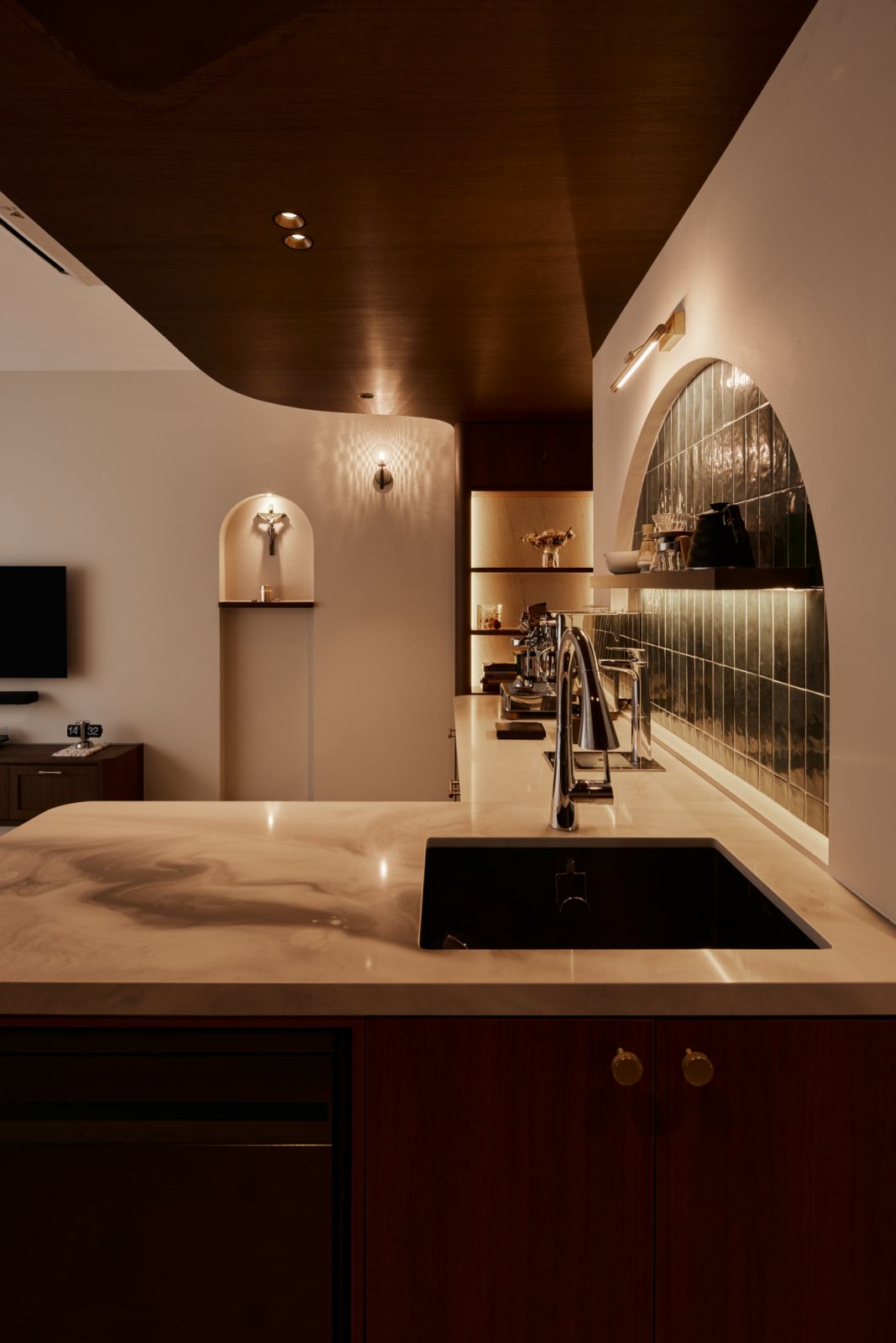 A closer look at the island’s fluid curves and veined stone surface, which lend a soft sculptural quality to the open-plan kitchen