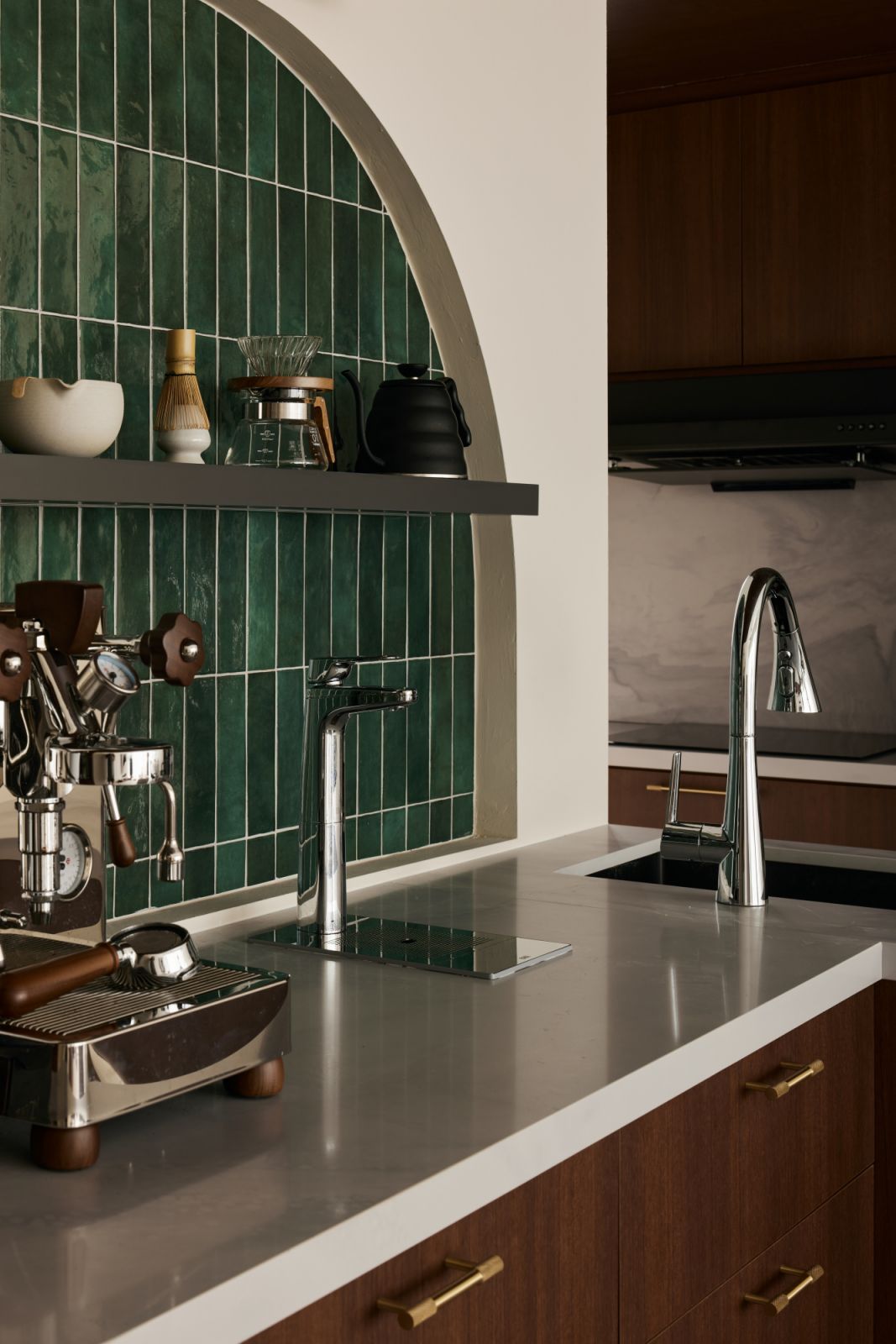 A detail of the arched backsplash, where artisanal green tiles and brushed brass accents highlight the home’s thoughtful material palette