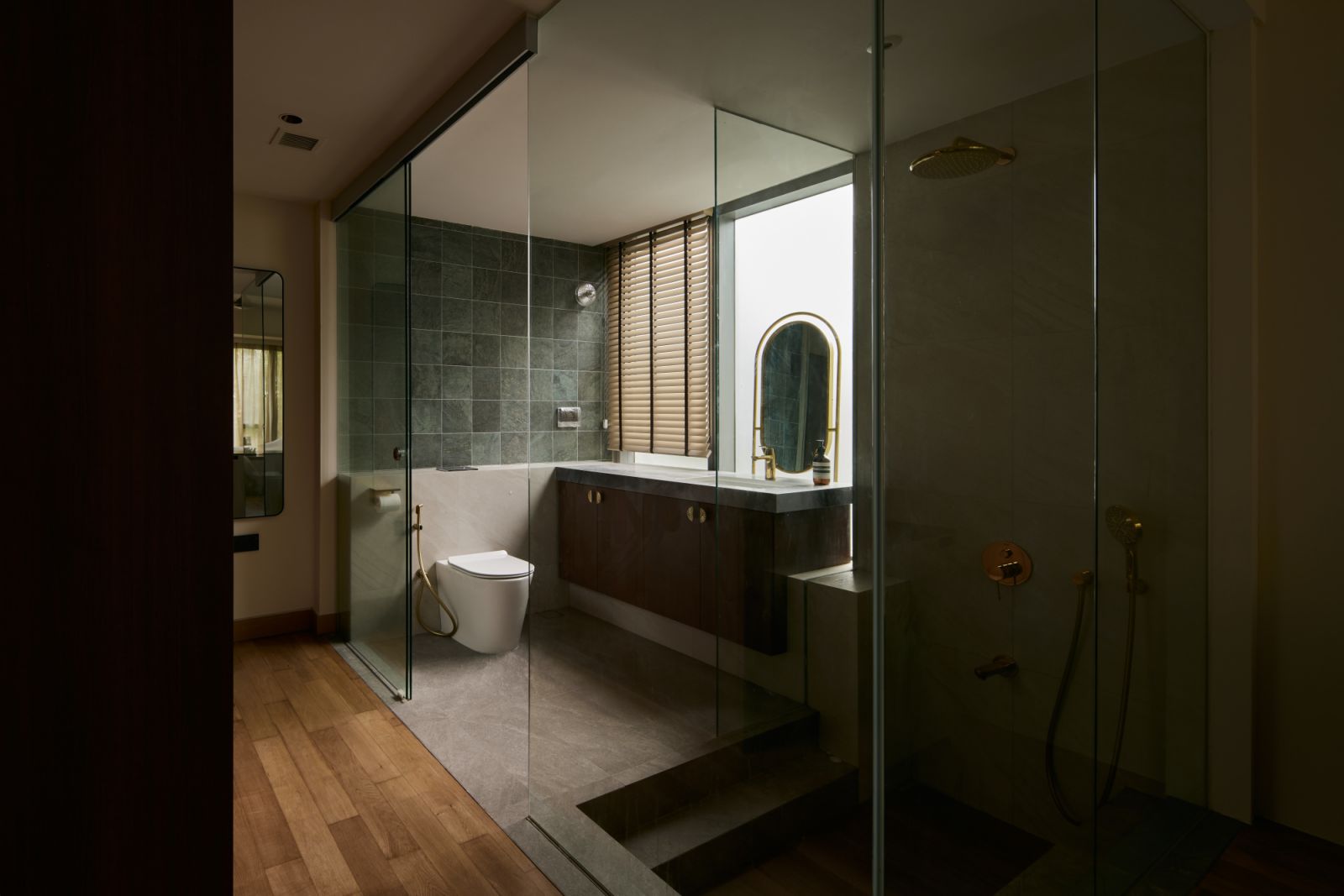 The spa-like master bathroom features a step-down shower, rich stone textures and soft lighting—fostering calm and relaxation