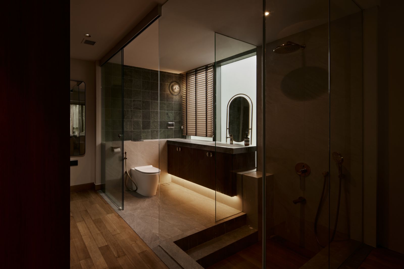 At night, the master bathroom takes on a moody elegance, where indirect lighting and deep finishes transform it into a private sanctuary
