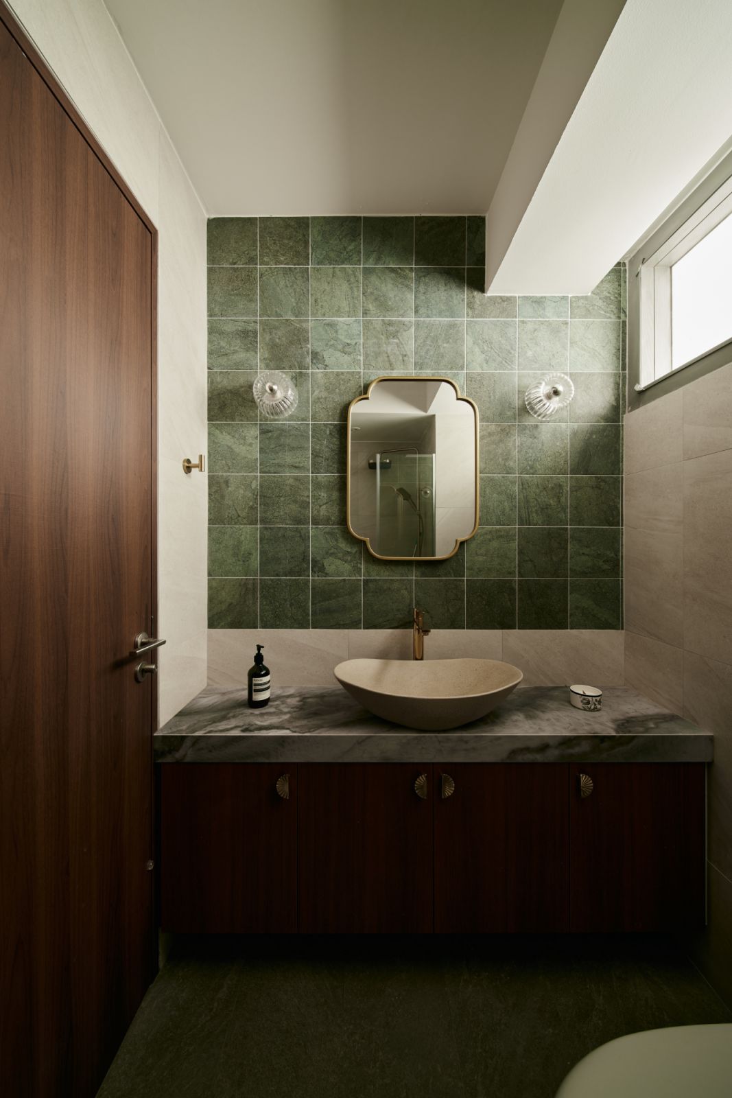 Natural daylight softens the contrast between the bold stone countertop and dark cabinetry, creating a serene and grounded visual rhythm